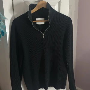 Svart ribbad half zip från Jack & Jones - Svart långärmad tröja från Jack & Jones med ribbad struktur och half zip-dragkedja i silver. Hög krage och stilren design som funkar till jeans eller chinos. Materialet känns mjukt och är troligtvis bomull eller polyester. Säljer för min bror inte kommer till användning med den!!! Jag har använt den på sommaren typ 2 gånger‼️ sedan har den bara legat i hans garderob 🥰Perfekt till din kille i present eller om en kille vill ha den till snygg vardag ☺️