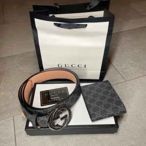 Svart bälte med plånbok - Snyggt svart bälte med klassiskt mönster. Bältet är gjort i skinn och har en lyxig känsla med detaljer i grått och svart. Perfekt accessoar för att lyfta din outfit.