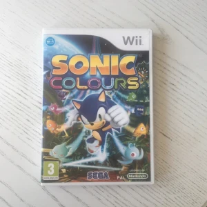 Sonic Colours (Wii) - Sonic Colours till Nintendo Wii i fint skick, komplett med fodral, manual och skiva. Ett fartfyllt plattformsspel där Sonic utforskar Dr. Eggmans nöjespark och använder färgglada krafter. Skivan ser ut att vara i gott skick utan synliga repor.