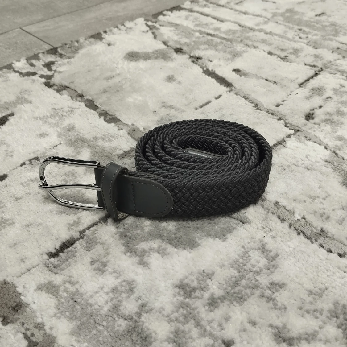 Grå flätat bälte med silverfärgat spänne