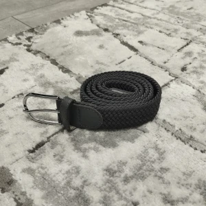 Grå flätat bälte med silverfärgat spänne - Snyggt gråt flätat bälte med silverfärgat metallspänne och detaljer i skinn. Bältet har en stilren design med flätad struktur som ger en cool och modern känsla. Perfekt för att lyfta din outfit och passar till både jeans och chinos. Vid fler frågor och funderingar är du varmt välkommen att fråga mig.
