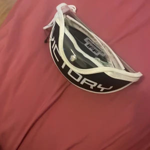 Unihoc innebandyglasögon grön/vit - Säljer ett par sportiga Unihoc innebandyglasögon med vit och grön båge samt elastiskt band med Unihoc-tryck. Glasögonen har en snygg, halvrund form och är rekommenderade av IFF. Perfekt för dig som vill ha stil och säkerhet på planen.