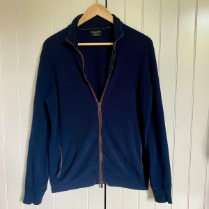 Stickad zip tröja från Massimo Dutti - Snygg marinblå kofta från Massimo Dutti i bomull. Modellen har hel dragkedja framtill, hög krage och ribbade muddar. Dragkedjan har en liten skada längst ner men ingenting som varken märks eller stör, storlek M men kan även passa någon som är mellan S och M, priset är inte hugget i sten😉