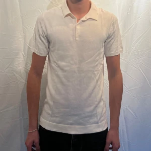  piké - Klassisk vit piké t-shirt med krage från H&M piken har knäppning framtill med två knappar och är tillverkad i ett mjukt bomullstyg. Passformen är normal och stilen är enkel och clean, perfekt för en stilren look. Modellen är 180cm