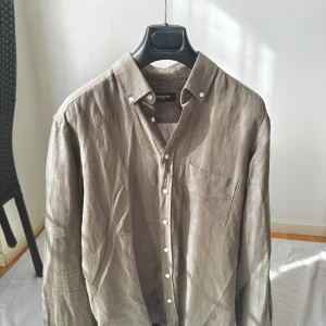 Grön linneskjorta från Lawrence Grey - Snygg grön skjorta i linne från Lawrence Grey. Klassisk modell med krage, vita knappar och bröstficka. Perfekt för dig som gillar en avslappnad men stilren look. Skjortan har lång ärm och en naturligt loose passform.