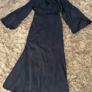 Marinblå långklänning från SHEIN - Snygg marinblå långklänning från SHEIN med vida långa ärmar och ett elegant draperat parti vid halsen. Klänningen har en mjuk, glansig yta och är tillverkad i ett syntetmaterial som ger ett lyxigt intryck. Perfekt för dig som gillar stilrena och sofistikerade looks.