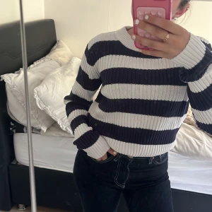 Randig stickad tröja i blått och vitt - Säljer en ribbstickad tröja med breda marinblå och vita ränder. Tröjan har rund halsringning och långa ärmar. Perfekt för dig som gillar en klassisk och chill stil.