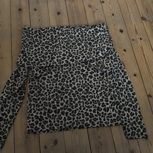 Leopardmönstrad offshoulder topp Kappahl - Säljer en snygg offshoulder topp från Kappahl i storlek M. Toppen har ett leopardmönster i beige och svart, långa ärmar och en bred volangkant upptill. Perfekt för dig som vill sticka ut med ett djurmönstrat plagg.