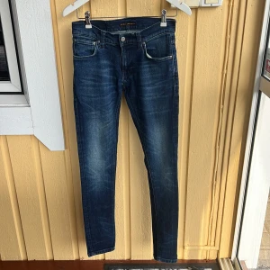 Mörkblå skinny jeans från Nudie Jeans - Snygga mörkblå jeans från Nudie Jeans i modellen skinny fit. Klassisk femficksdesign med diskreta slitningar och broderade bakfickor. Jeansen har normal midja och är tillverkade i stretchig bomull för en bekväm passform. Storlek 16y 164 cm