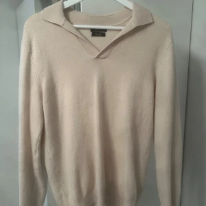 Beige ulltröja med krage från Massimo Dutti - Säljer en stilren beige tröja från Massimo Dutti i exklusiv ull. Tröjan har en snygg krage med v-ringning och långa ärmar. Perfekt för lager-på-lager och passar till både jeans och kostymbyxor. Tröjan är i storlek M men passar S bättre.