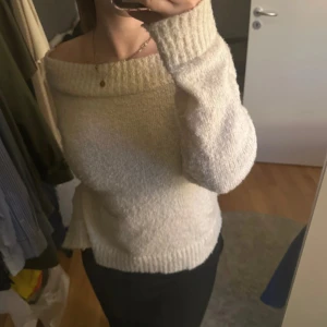 Offshoulder stickad vit tröja - Mysig offshoulder stickad tröja i vit färg med bred ribbad kant upptill. Tröjan har lång ärm och en loose passform, perfekt för lager på lager under kyliga dagar. Enkel att styla med både jeans och kjol. Perfekt nu till hösten 😍