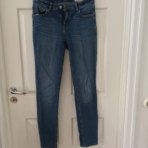 Blå jeans med normal midja - Snygga blå jeans med slim passform och normal midja. Klassisk femficksmodell med dragkedja och knapp framtill. Jeansen har en lätt tvättad look och är tillverkade i stretchigt jeansmaterial för extra komfort.