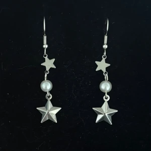 Silvriga örhängen med stjärnor och pärlor - Handgjorda och unika silverörhängen 🤩 Öronhängerna är nickelfria och silverpläterade i kirurgiskt stål, resterande av örhänget är i rostfritt stål (ej silverpläterat) 💕🙏 4.5 cm långa. Alla köp görs via ”KÖP NU” knappen.  💐