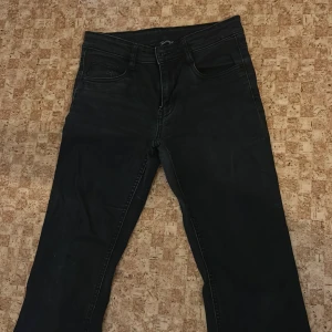 Svarta jeans från Instinct - Svarta jeans från Instinct med bootcut och klassisk femficksdesign. Jeansen har snygga bakfickor med lock och silverfärgade knappar. Tillverkade i jeansmaterial och har en stilren look som passar till många outfits.