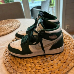 Nike Air Jordan 1 high grön/vit - Säljer ett par Nike Air Jordan 1 high i grönt och vitt skinn. Klassisk high-top siluett med gröna snören, vit bas och gröna detaljer. Ikonisk vinge-logga på sidan och Nike-märke på plösen. Perfekta för dig som vill sticka ut med snygga sneakers.