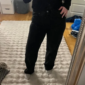 Svarta 90s straight jeans midja 32 - Säljer ett par svarta jeans i klassisk 90s straight modell med rak passform och normal midja. Byxorna har fem fickor och stängs med knapp och dragkedja. Perfekta för dig som gillar en enkel och tidlös look.