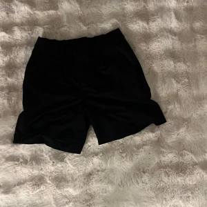 Svarta shorts från 157 i storlek M - Svarta shorts från 157 i storlek M. De har en enkel och stilren design med elastisk midja och raka ben. Perfekta för en chill och avslappnad look. Materialet känns mjukt och lätt, vilket gör dem sköna att bära under varmare dagar.