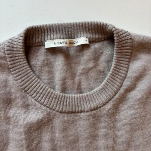 Beige stickad tröja från A Day's March - En stilren beige stickad tröja från A Day's March med rund halsringning och ribbade muddar. Perfekt för lager-på-lager och funkar året runt. Enkel och klassisk design som är lätt att matcha med allt.