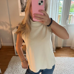 Ärmlös polotopp i offwhite - Säljer en stilren ärmlös polotopp i offwhite med hög, ribbad krage. Toppen är stickad och har en rak passform. Så så så fin!!💞💞