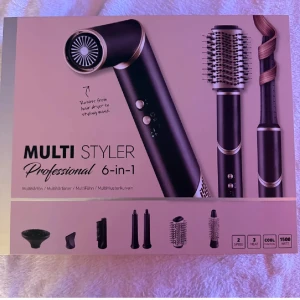 Multi Styler Professional 6-in-1 - Multi Styler Professional 6-in-1 är ett mångsidigt stylingverktyg med 1500W, 3 värmelägen, 2 hastigheter och flera tillbehör för lockar, volym, torkning och styling. Snygg svart/guld design, passar alla hårtyper. Produkten är ny i originalförpackning.