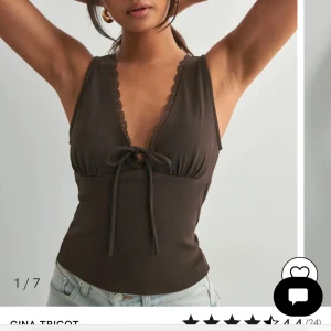 Brun ribbad linnetopp från Gina Tricot - Supersnygg brun linnetopp från Gina Tricot med djup v-ringning, spetskant och knyt framtill. Toppen är ribbad och ärmlös, perfekt att styla med jeans eller kjol för en trendig look. Mjuk och stretchig i materialet för skön passform. Aldrig använd!💓