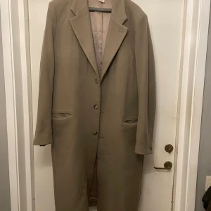 Beige kappa från HOPE Stockholm - Stilren beige kappa från HOPE Stockholm med klassisk krage och tre knappar framtill. Långa ärmar, perfekt för hösten. Nypris ca 6500
