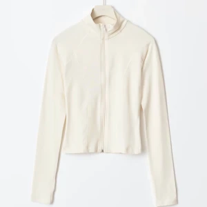 Vit tränings jacka från Gina tricot  - Säljer en fräsch vit kofta från Gina tricot med slim passform och hel dragkedja framtill. Tröjan är långärmad och har en hög krage, perfekt för lager-på-lager. Materialet är mjukt och stretchigt, vilket gör den superbekväm. Använd fåtal gånger, i fint skick.💞