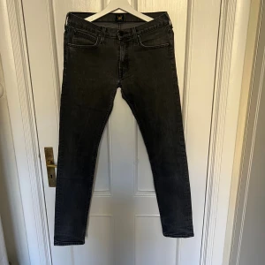 Svartgrå skinny jeans från Lee - Snygga svarta jeans från Lee med klassisk femficksdesign och skinny passform.  Säljer då byxorna är för tajta för min smak. Riktigt bra skick, storlek W29 L32. Endast 129kr!
