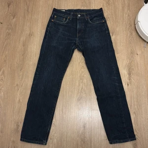 Levi's 502 mörkblå jeans straight fit - Klassiska Levi's 502 jeans i mörkblå denim med raka ben och femficksdesign. Byxorna har normal midja, knappgylf och snygga kontrastsömmar. Perfekta för dig som gillar en tidlös och clean look.