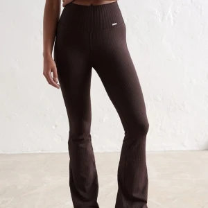 Bruna ribbade bootcut byxor Aim'n XS - Mörkbruna ribbade byxor från Aim'n i stretchigt material. Hög midja och bootcut-modell som sitter tajt upptill och släpper vid benen. Perfekta för en chill och trendig look. Supersköna och snygga till sneakers eller boots.