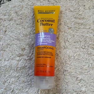 Marc Anthony Coconut Butter Shampoo - Brightening Coconut Butter Hydrating Shampoo för blont hår med kamomill. Tuben är 250 ml och har en snygg gul, lila och orange design. Formulan är lätt och fri från sulfater, parabener och ftalater. Perfekt för att fräscha upp blonda nyanser.