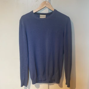 Blå tröja från Bruun & Stengade - En stilren blå tröja från Bruun & Stengade i storlek S. Tröjan har rund halsringning, ribbade muddar och är långärmad. Perfekt för dig som gillar en klassisk look med enkel design. Priset är inte hugget i sten. 