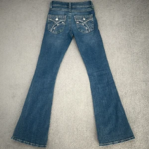 Blå bootcut jeans Gina Tricot XS - Snygga blå bootcut jeans från Gina Young 14+  i storlek XS. Jeansen har låg midja och coola broderade detaljer på bakfickorna. Klassisk femficksmodell i mjukt denimtyg. Använda 5 gånger! 