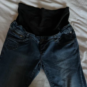 Mörkblå mamma jeans med stretchpanel - Mörkblå jeans med hög midja och bred svart stretchpanel för gravidmage. 