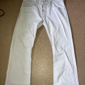 Levi's 512 vita bootcut jeans - Snygga vita Levi's 512 jeans med bootcut passform. Klassisk femficksdesign, bakficka med knapp och tydlig Levi's patch baktill. Jeansen är tillverkade i mjukt bomullsmaterial och har en stilren look som passar till sneakers eller boots.