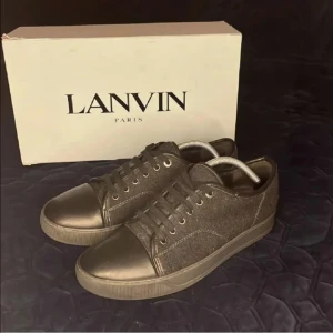Lanvin skor - Snygga svarta sneakers från Lanvin med ovandel i ull och tå samt detaljer i svart skinn. Klassisk rund tå, platt sula och snörning framtill. Perfekta för dig som gillar stilrena och exklusiva sneakers med en lyxig känsla. Box eller dust bag medföljer ej.