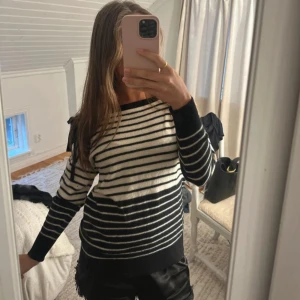 Randig tröja Sonia Rykiel med rosett - Superfin randig tröja från Sonia Rykiel x HM i svart och vite med broderad logga på ärmen. Tröjan har lång ärm, båtringad hals och en söt rosettdetalj på axeln. Mjuk och skön, perfekt till jeans eller kjol. 100% ull 