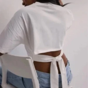 Vit croppad topp med knyt i ryggen - Säljer en vit croppad topp med kort ärm och snygg knytning i ryggen. Toppen har en enkel och clean look framtill och öppen rygg med band som knyts. 💕💕