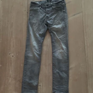 Gråa slim fit jeans - Snygga grå jeans med smal passform och klassisk design. Perfekta för dig som gillar en stilren och enkel look. Materialet är mjukt och följsamt för extra komfort.