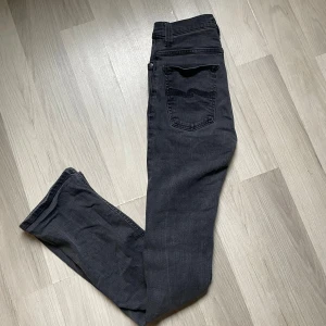 Svarta jeans från Nudie Jeans Co - Snygga svarta jeans från Nudie Jeans Co Jeansen har smal passform och är tillverkade i mjukt denimtyg.                                                                   W28 L32      
