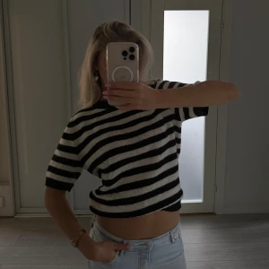 Randig svartvit stickad tröja H&M - Säljer en stickad, kortärmad tröja från H&M i storlek S. Tröjan är svart och vit med breda horisontella ränder och har en lite croppad passform. Perfekt till jeans eller kjol för en chill och trendig look.