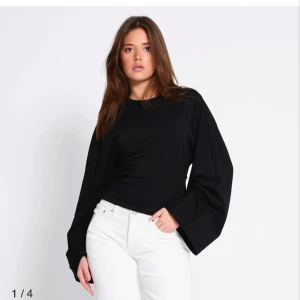 Svart långärmad topp med vida ärmar - Svart långärmad topp från 157 med riktigt vida ärmar och rund halsringning. Modellen är croppad och har en clean, minimalistisk look. Perfekt för dig som gillar statement-ärmar och enkel stil.