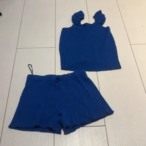 Blå ribbade shorts från H&M - Säljer ett par blå ribbade shorts från H&M. De har elastisk midja och är tillverkade i ett mjukt, stickat material som ger en skön och avslappnad känsla. Perfekta för varma dagar och matchar snyggt med ett linne eller t-shirt.