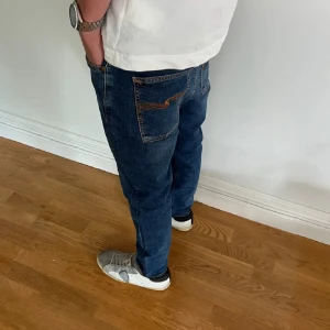 Nudie Jeans - Snygga blå jeans från Nudie Jeans med klassisk femficksdesign och kontrastsömmar på bakfickorna. Jeansen har en rak passform och är tillverkade i mjukt denimtyg av bomull. Perfekta för en avslappnad och stilren look. Slim fit