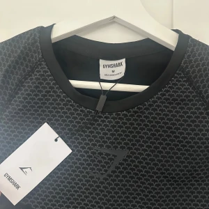 Gymshark Onyx - Gymshark Onyx V2. Storlek M  Helt ny och oanvänd, tröjan är i nyskick!  Pris går o diskutera vid snabb affär. Hör av dig vid några frågor eller funderingar!