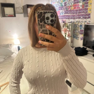 Ljusrosa aktig gant tröja  - Säljer en klassisk vit kabelstickad tröja från Gant i stretchig bomull. Tröjan har rund halsringning, ribbade muddar och Gant-logga broderad på bröstet. Perfekt för dig som gillar en stilren och tidlös look. Tröjan är äkta!!