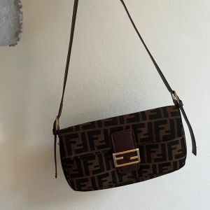 Liten axelväska - Köpt på Plick. Jag har klippt av bandet då det var långt från början. Ej i skinn! 