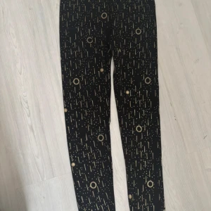 Svarta leggings med guldmönster - Snygga svarta leggings med unikt guldmönster av prickar och cirklar. Stretchigt material som sitter tight och bekvämt. Storlek s-m