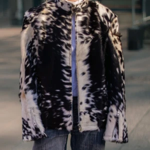 Cowprint pälsjacka med dragkedja - Unik pälsjacka med svartvita och brunvita ko-inspirerade mönster. Jackan har rak passform, dragkedja framtill och klassisk krage. Pälsimitationen ger en cool och trendig look som sticker ut. Perfekt för dig som vill ha något annorlunda och vågat.