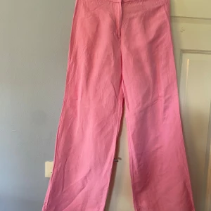 Rosa linnebyxor från H&M, strl 38 - Säljer ett par ljusrosa linnebyx liknande byxor från H&M i storlek 38. Byxorna har en relaxed wide fit med raka ben och stängs med dragkedja och hake. Materialet är en skön linneblandning som känns luftigt och fräscht. Perfekt för dig som gillar färg och vill sticka ut. Bara använda 2-3 ggr.